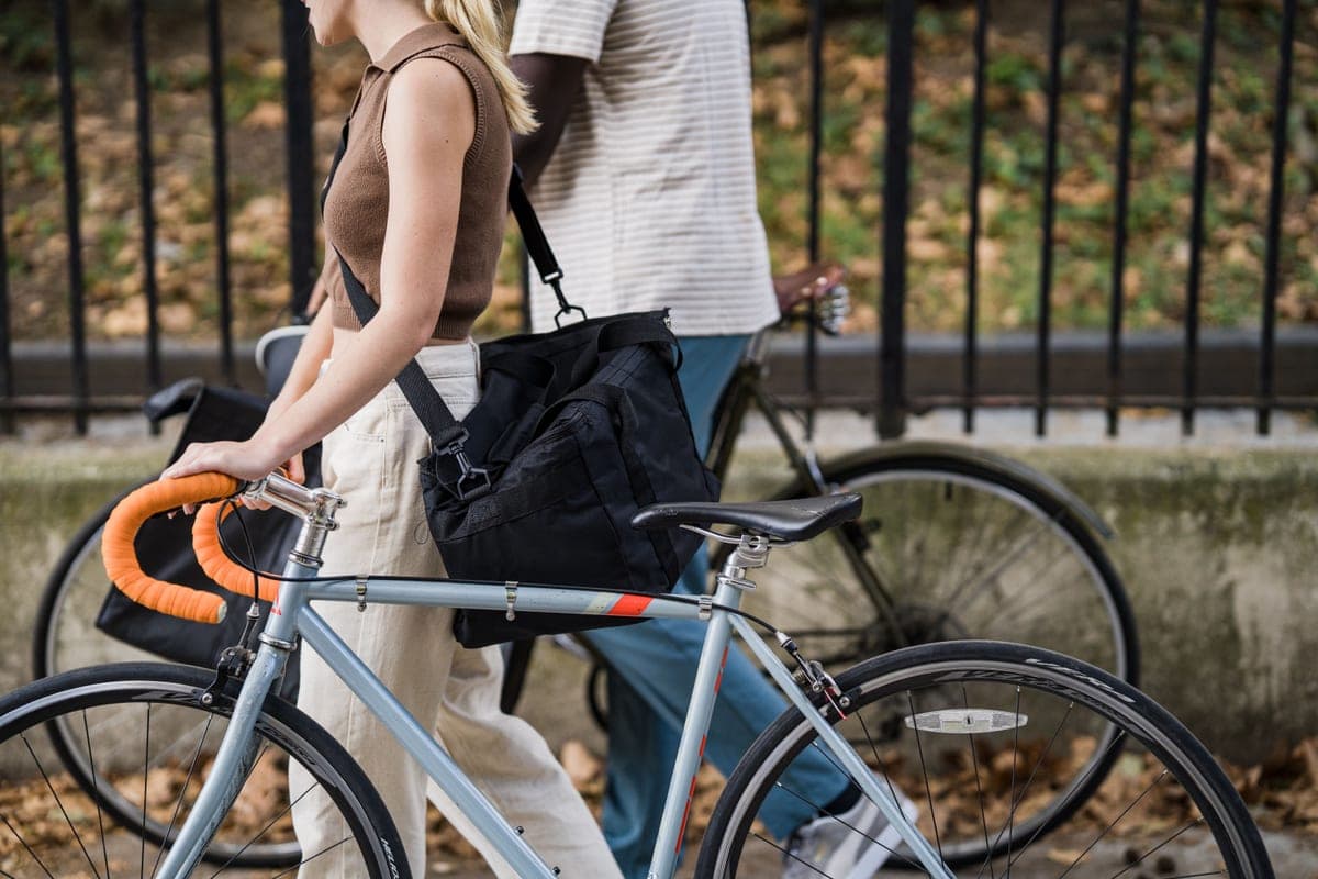 People riding bikes through the city carrying bags